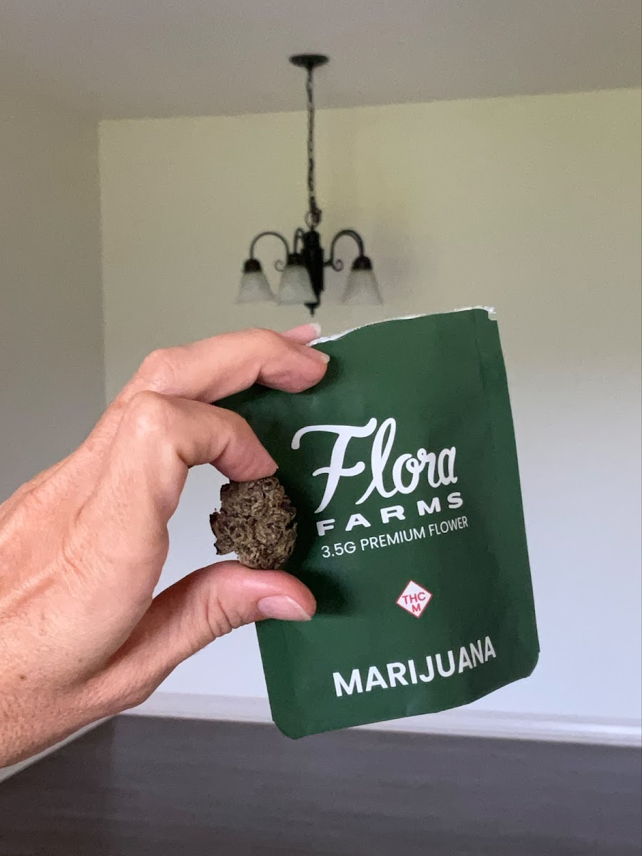 Hand holding Flora Farms 3.5G Premium Flower package.